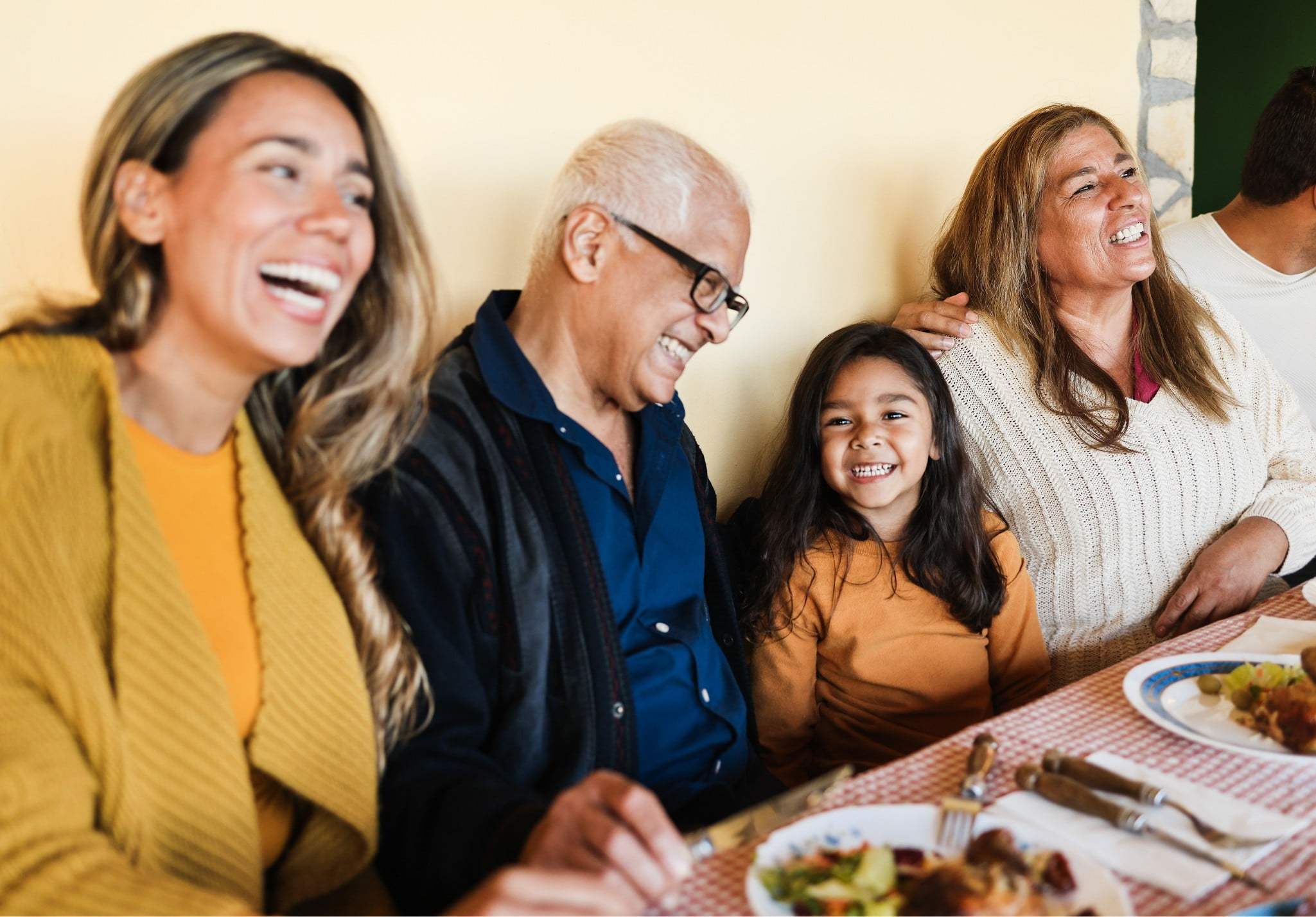 A family all sitting at a dinner table laughing and enjoying dinner together.
