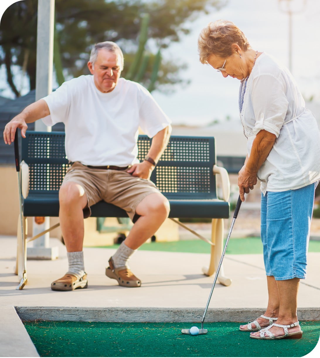 an elderly couple playing a game of mini golf.