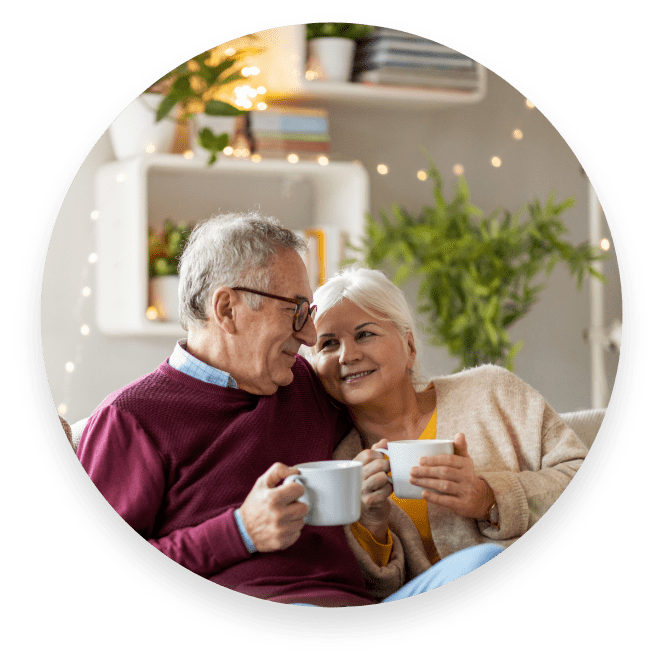 A picture of a couple on a couch having a coffee.
